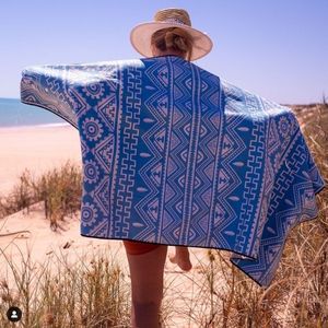 woman in hat with evolve sand free beach towel climbing over sand dunes