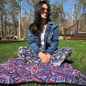 woman sitting on sand free beach towel in a park, smiling