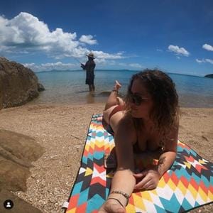 customer enjoys her evolve sand free towel on the beach